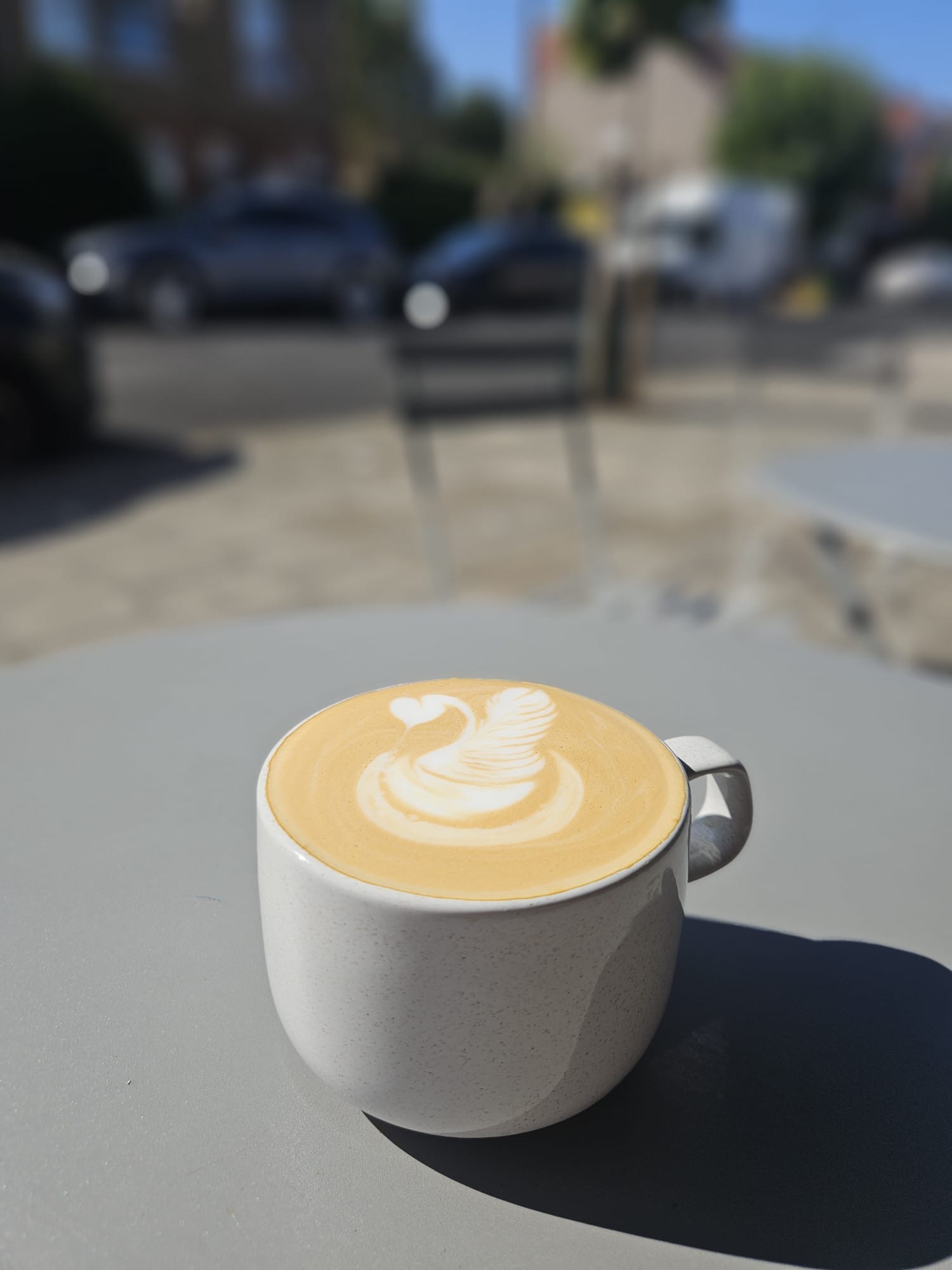 Latte with swan art enjoyed outside Front Room Coffee